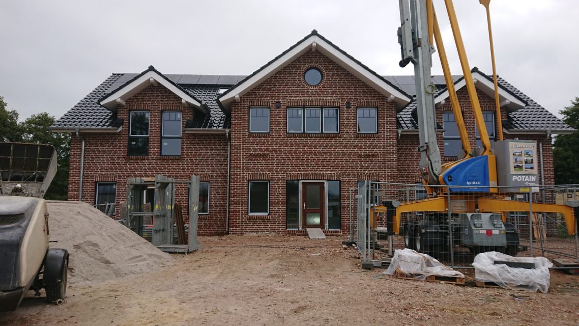 Fenster und Türen sind jetzt drin Neues, zweigeschossiges Haus im Bau mit roten Ziegeln und Konstruktionstechnik.