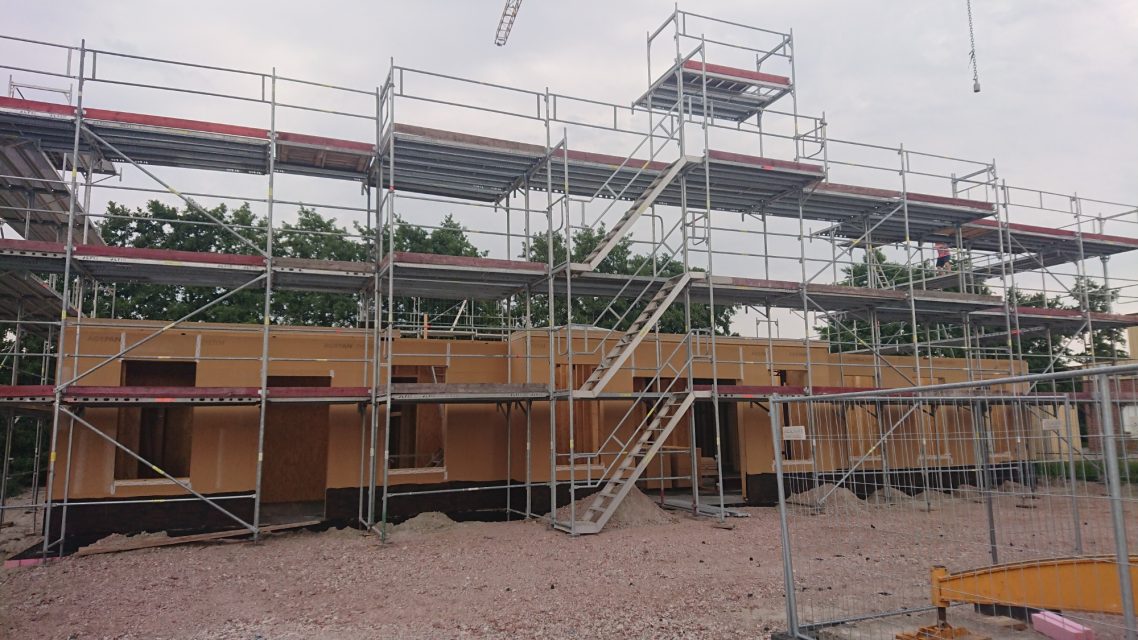 Jetzt geht es in die Höhe Baugerüst um ein mehrstöckiges Gebäude mit Holzpaneelen.