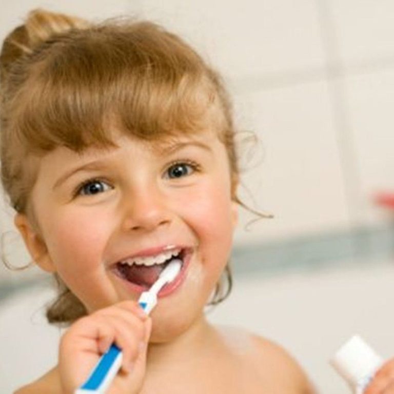 Lächelndes Mädchen putzt sich die Zähne in einem Badezimmer.