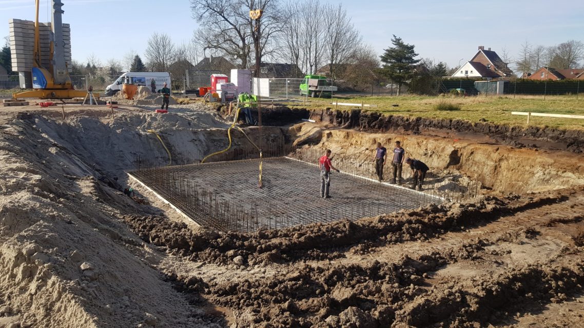 Bodenplatte Baustelle mit Fundamentaushebung und mehreren Bauarbeitern in einem ausgehobenen Bereich.