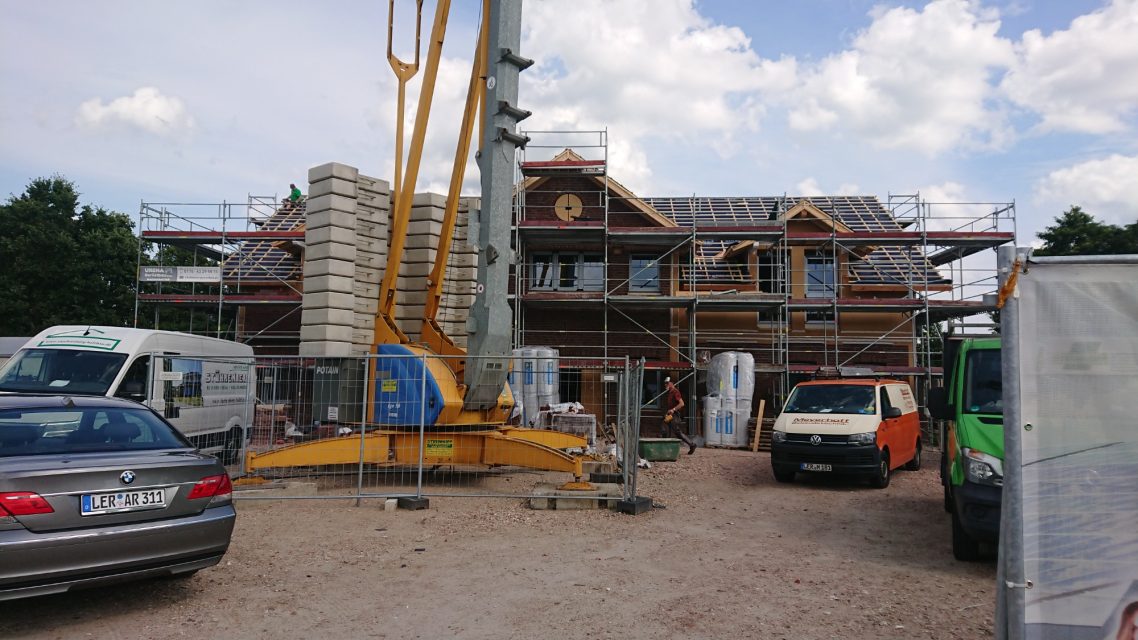 Das Dach ist gedeckt Neubau eines Hauses mit Baugerüst, Fahrzeugen und Baustellenausrüstung.