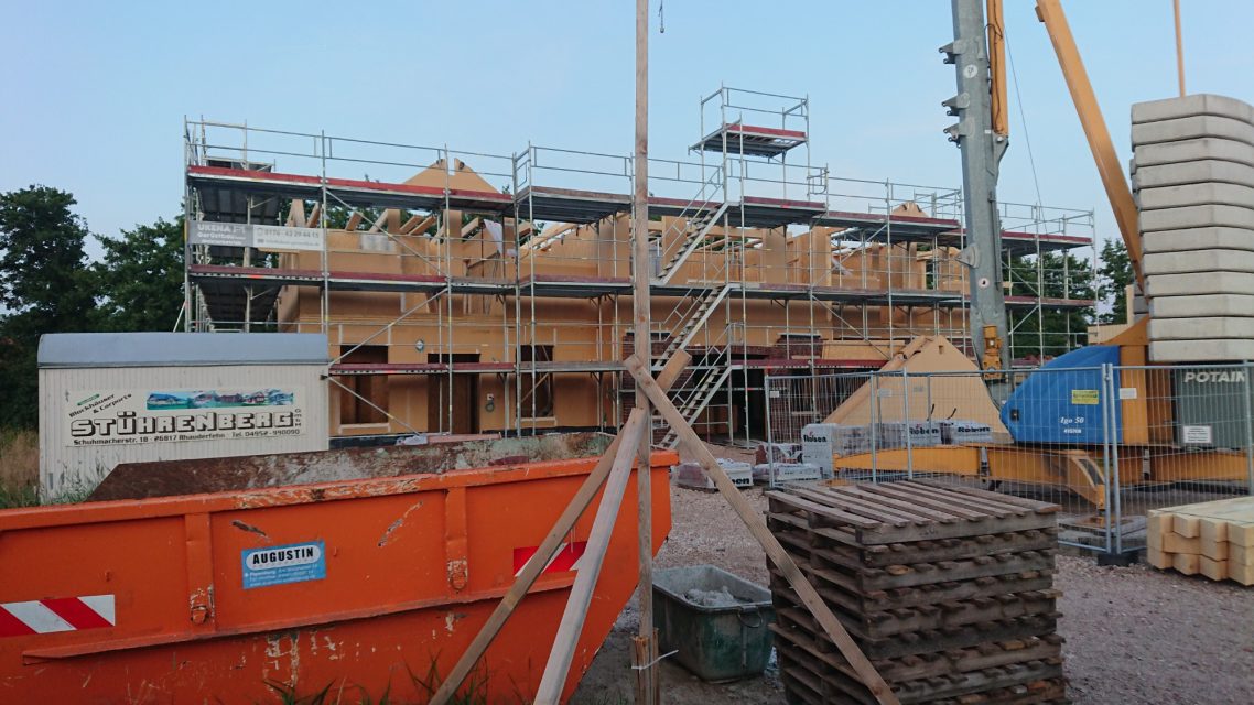 Die Praxis nimmt Form an Bauarbeiten an einem Holzgebäude mit Baugerüst und Baustellenmaterial.