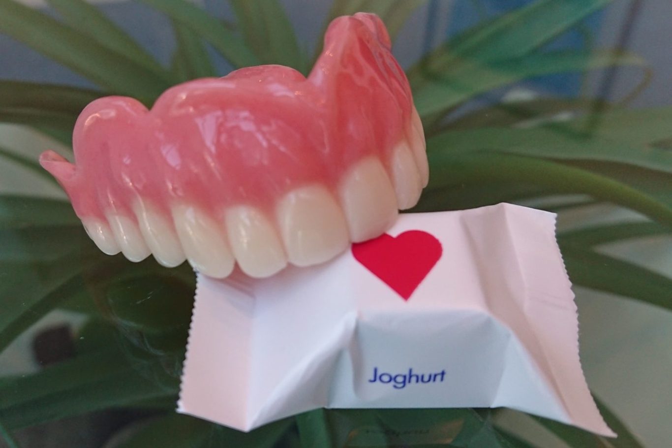 Prothesen Zahnersatz auf einem Tisch mit einer liebevollen Verpackung darunter.