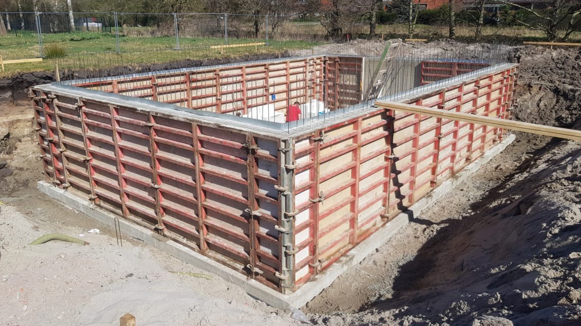 Baugrube Baugrube mit Holzschalung für ein Fundament, umgeben von Erdboden.