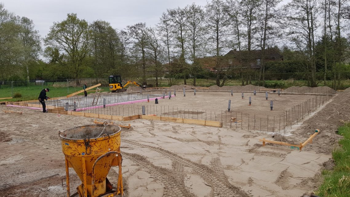 Langsam bewegt sich was Bauplatz mit Fundamentarbeiten und Baumaschinen in einer offenen Landschaft.